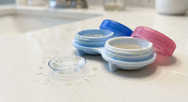 Contact lens beside a lens case with subtle microscopic bacteria around them